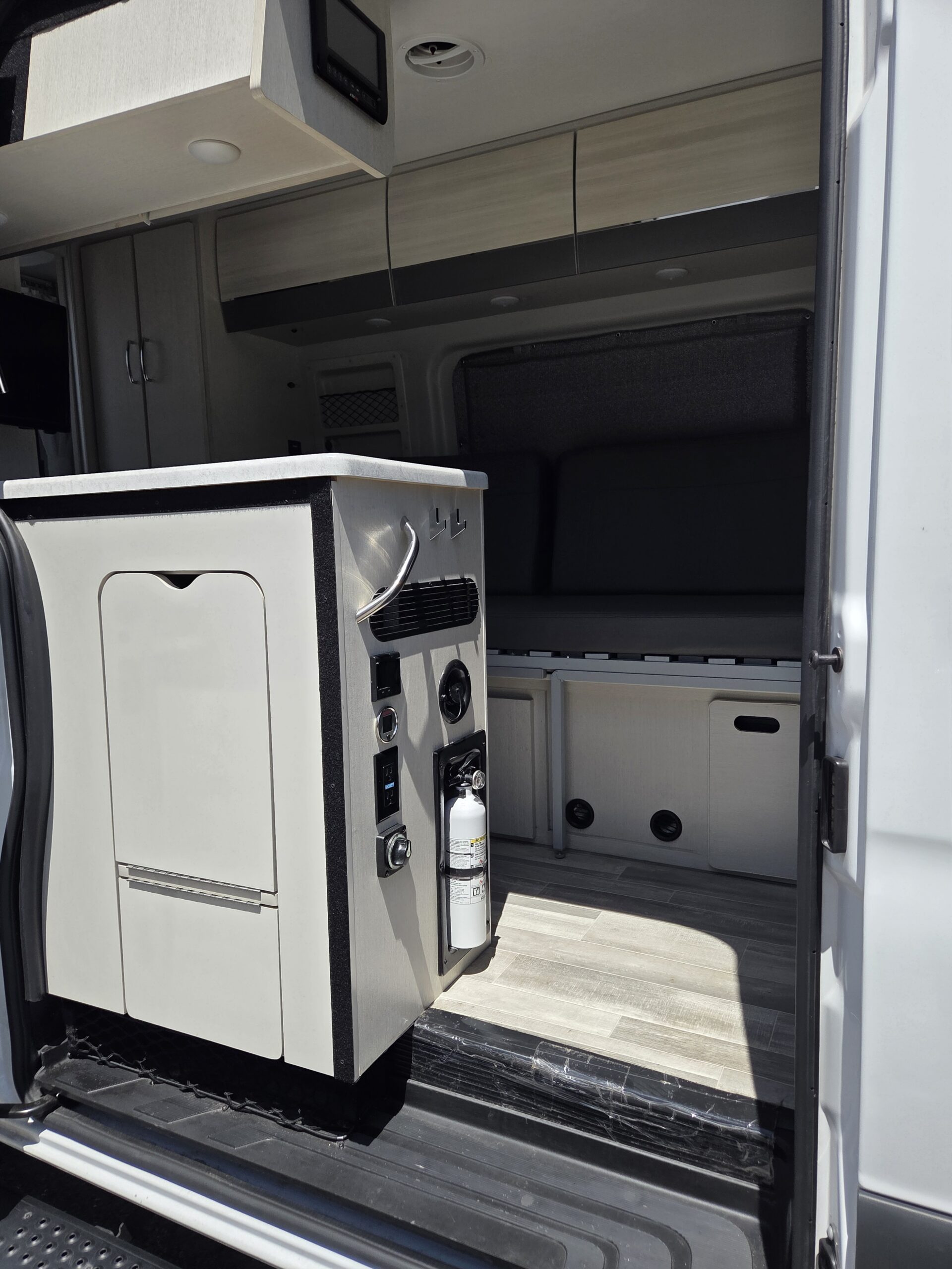 RV kitchenette and seating area detailed with wiped counters and spotless cabinetry.